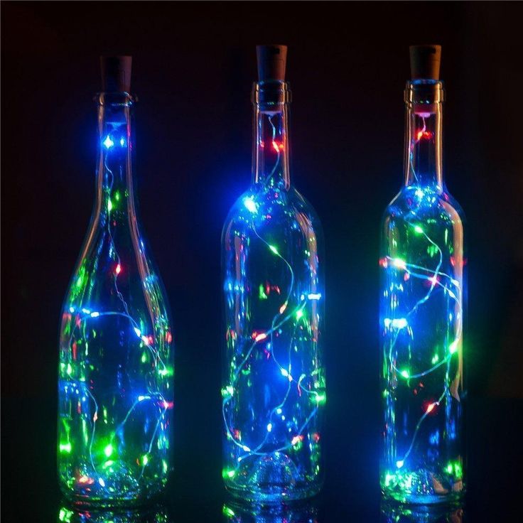 three bottles with lights in them sitting next to each other