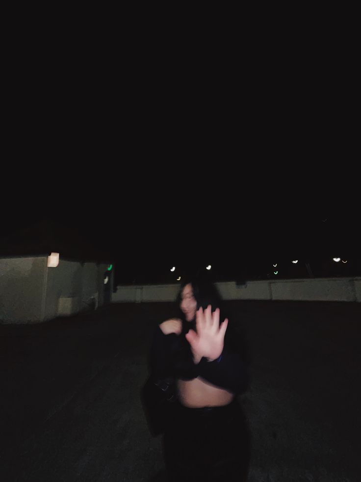 a person sitting in the middle of an empty parking lot with their hand up to her face