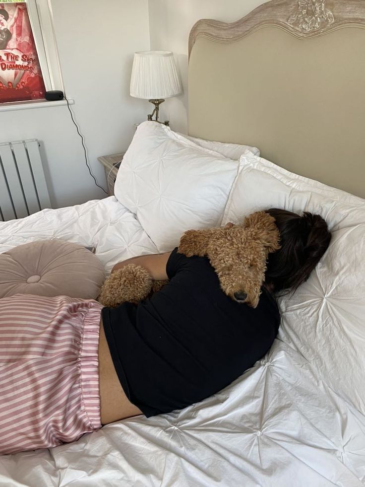 a woman laying on top of a bed next to a teddy bear wearing a dress