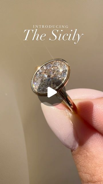 a close up of a person's hand holding a ring with a diamond on it