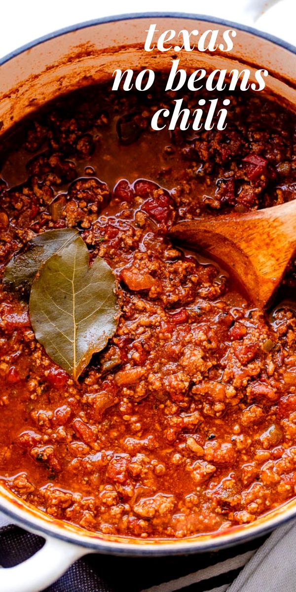 a large pot filled with chili and a wooden spoon in it, on top of a table