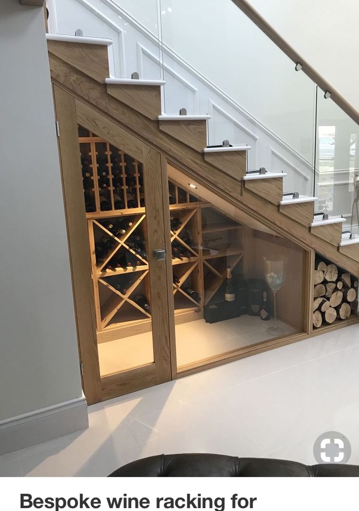 a living room filled with furniture and a wine rack under a stair case next to a glass door