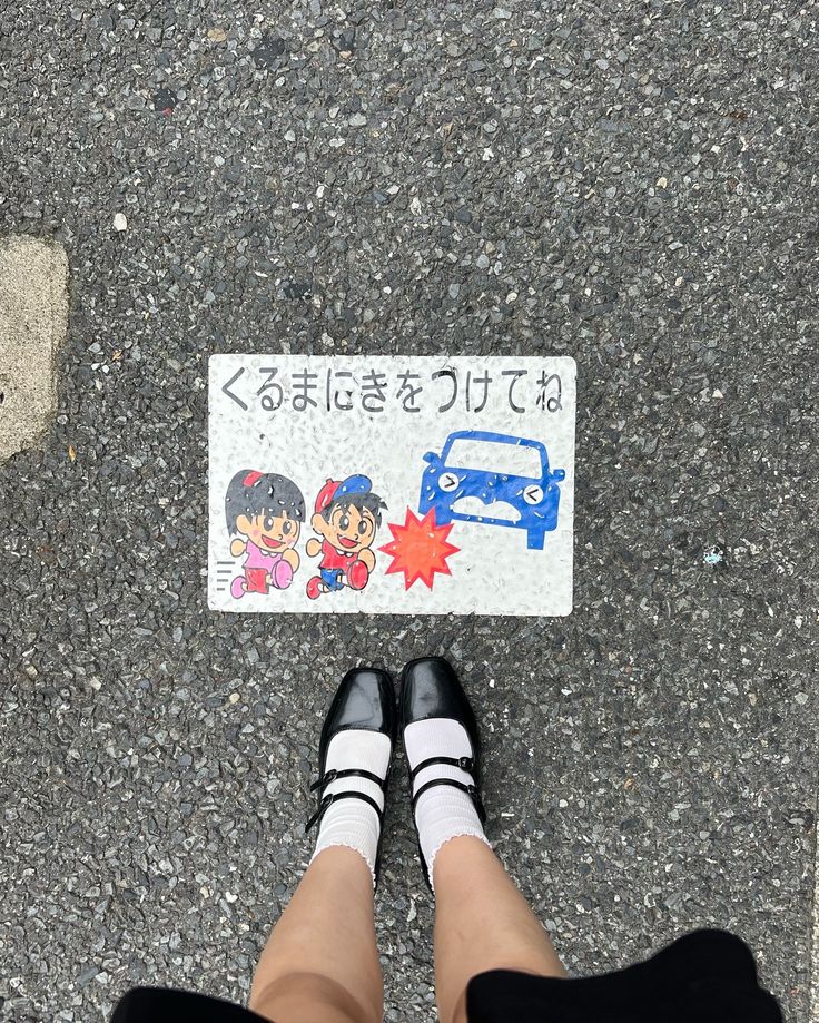 a person standing next to a street sign on the ground with their legs crossed and feet propped up