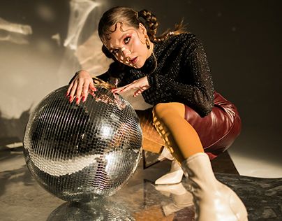 a woman sitting on top of a shiny disco ball