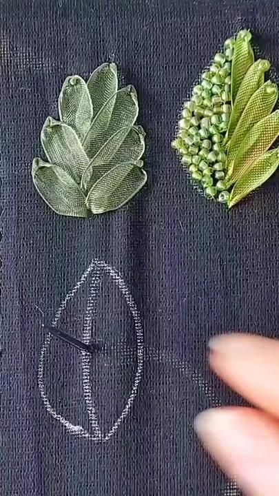 three different types of leaves on a piece of black fabric with stitching in the middle