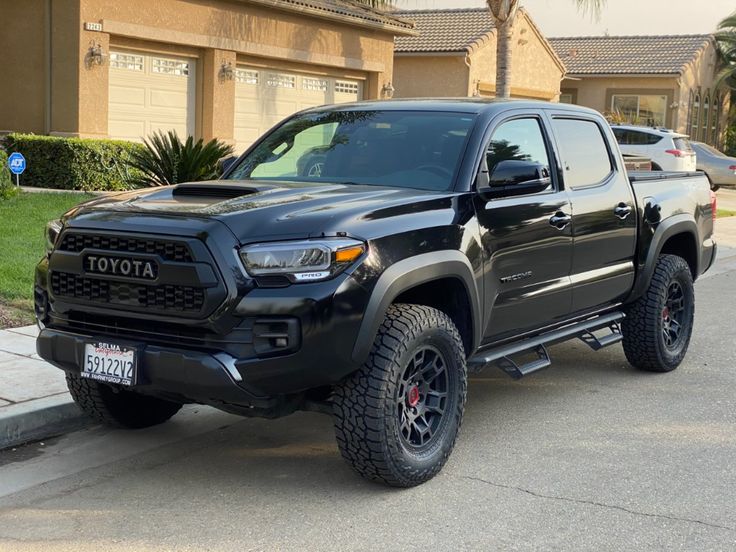 a black toyota truck parked in front of a house