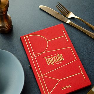 a red book sitting on top of a table next to silverware