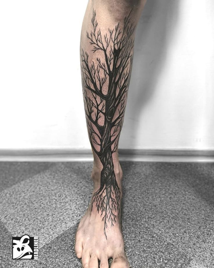 a man's bare foot with a tree tattoo on his left leg and bottom half