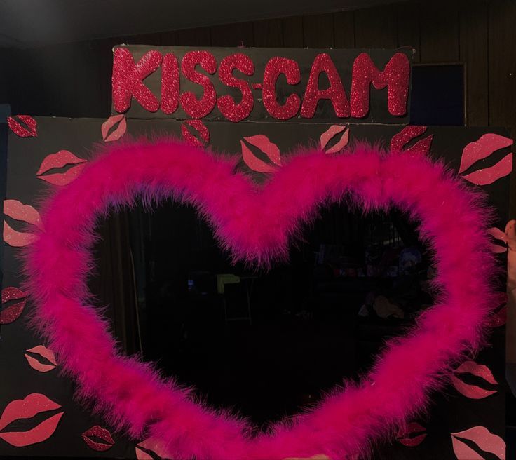 a valentine's day decoration with pink feathers and lipstick on the wall behind it