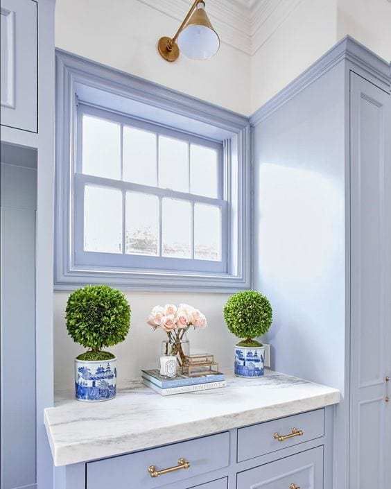 two vases with flowers on top of a white counter in a blue and white kitchen