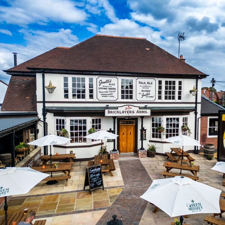 the outside of a restaurant with tables and umbrellas on it's patio area