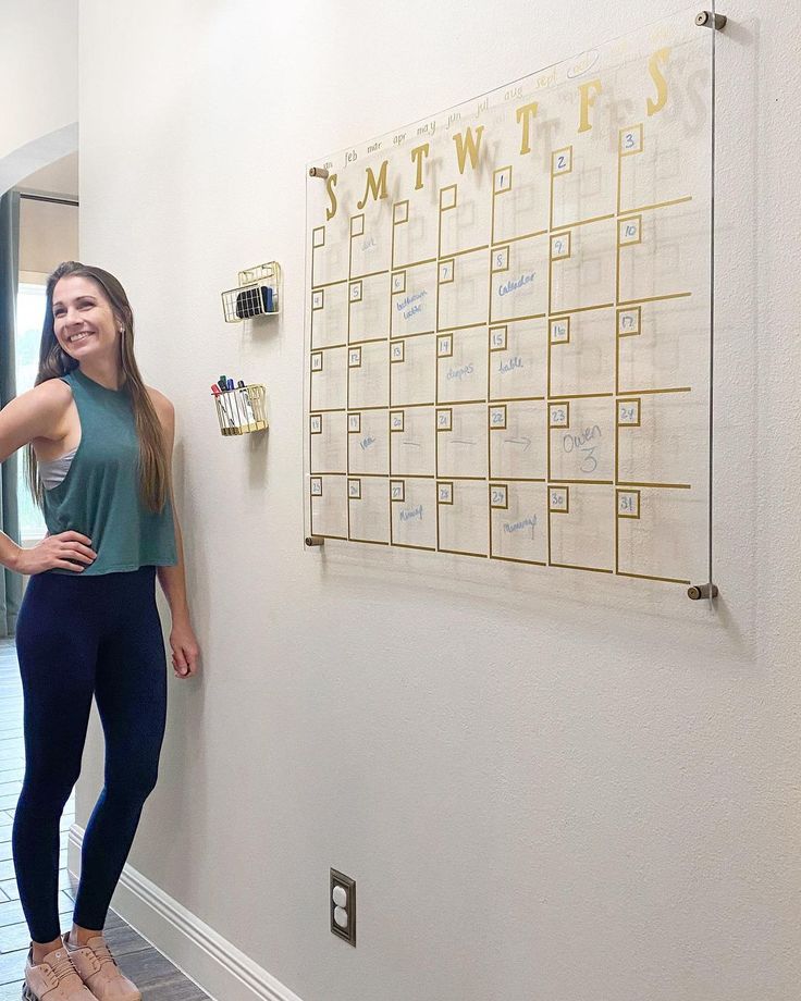 a woman standing next to a wall with a calendar on it