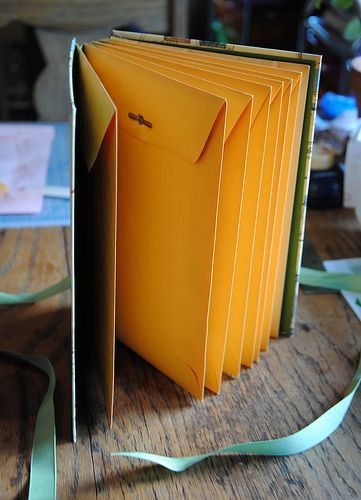 a stack of yellow folders sitting on top of a wooden table next to each other