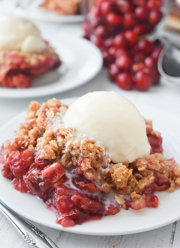 a plate topped with ice cream and crumbled berry cobbler next to two spoons