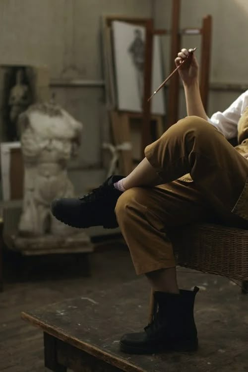 a woman sitting on top of a wooden table holding a stick in her hand and looking at the camera