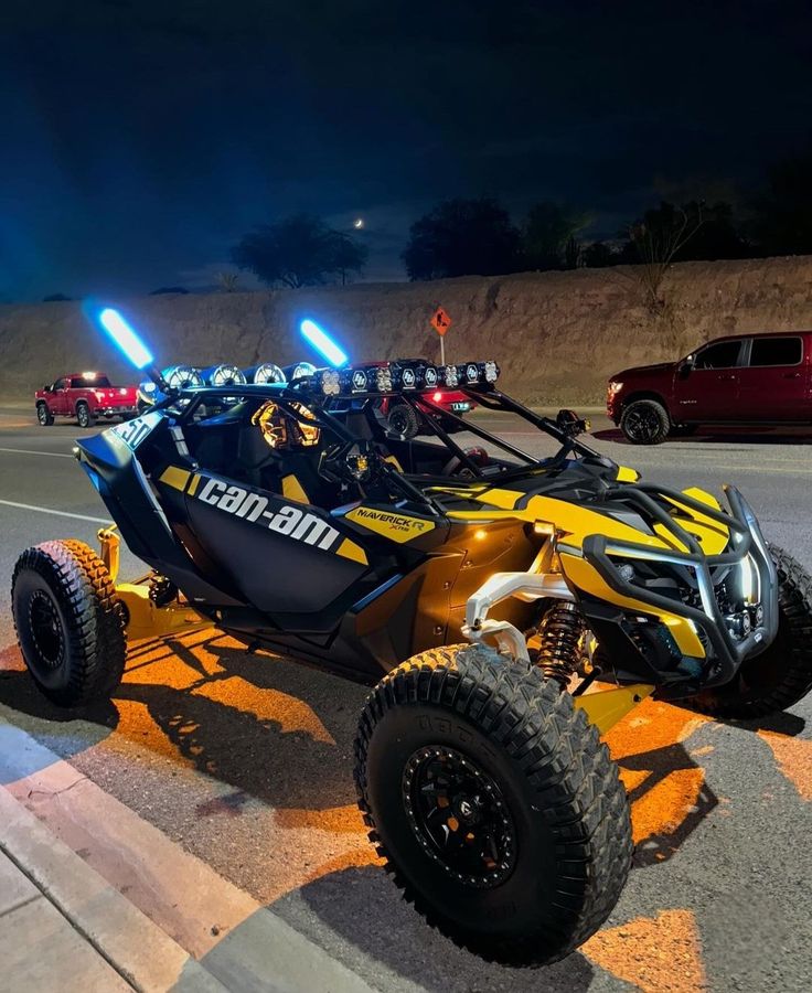 a yellow and black dune buggy driving down the road at night with lights on