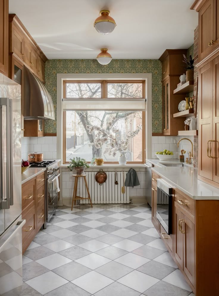 a kitchen with wooden cabinets and tile flooring next to a large window that looks out onto the trees outside