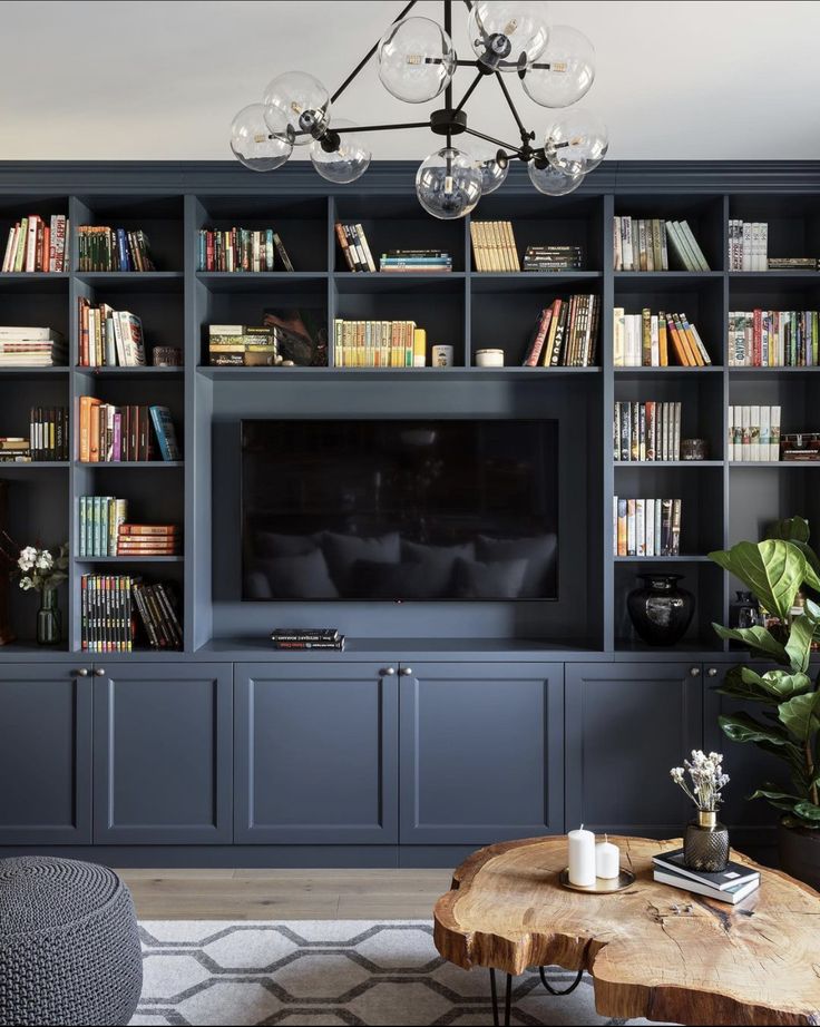 a living room with blue bookcases and a large tv on the far wall