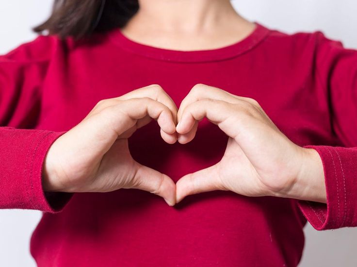 a woman making a heart shape with her hands