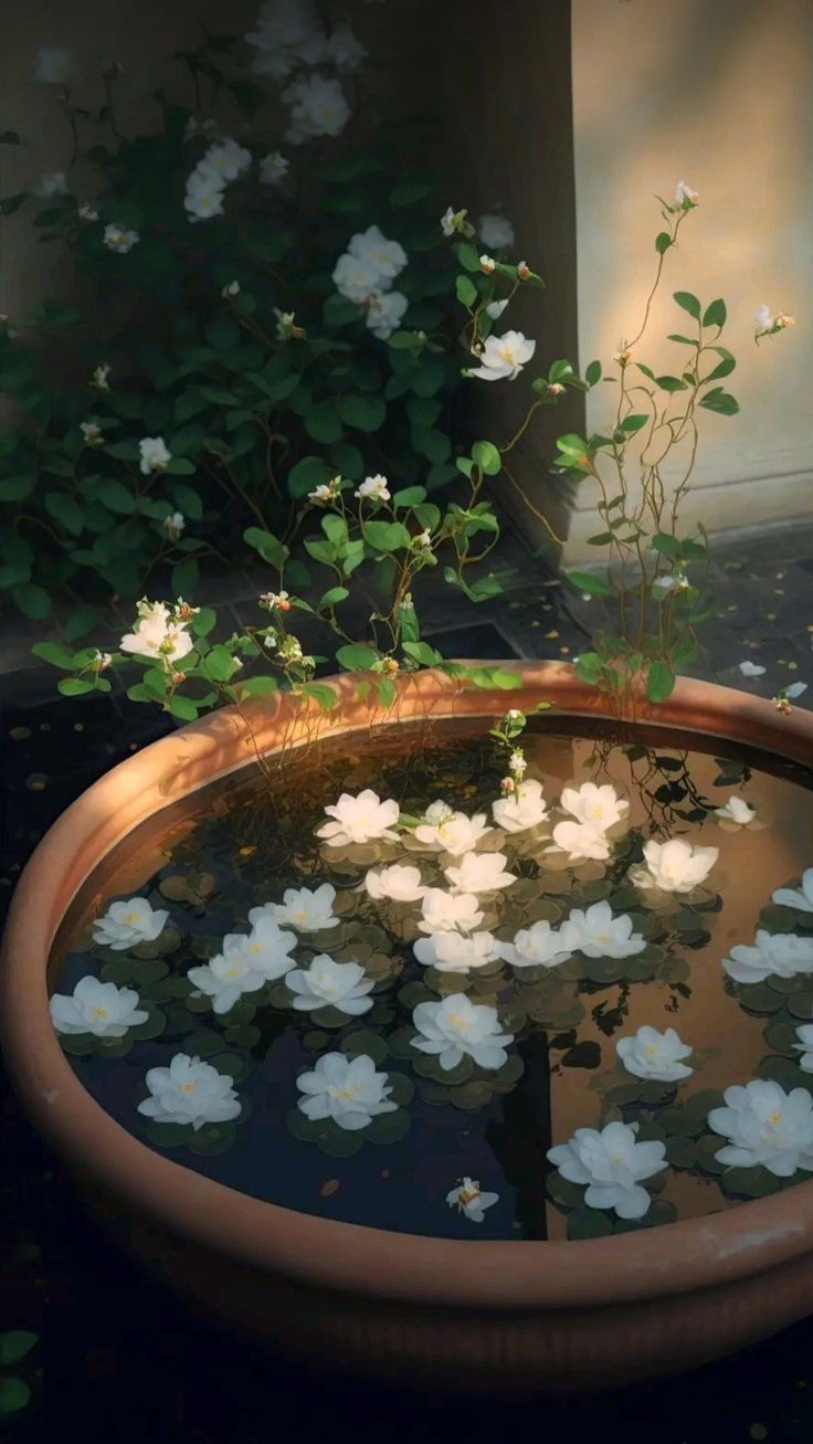 a potted plant with white flowers in it sitting on top of a water fountain