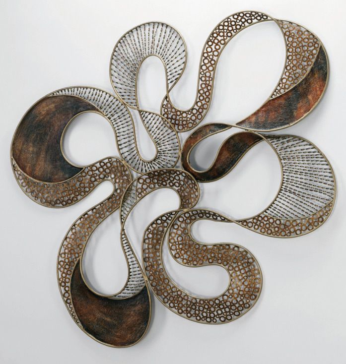 a metal wall sculpture on a white background with an intricate design in the center and bottom