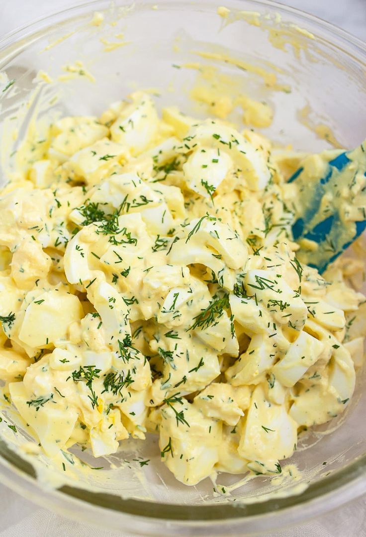 a glass bowl filled with potato salad on top of a table