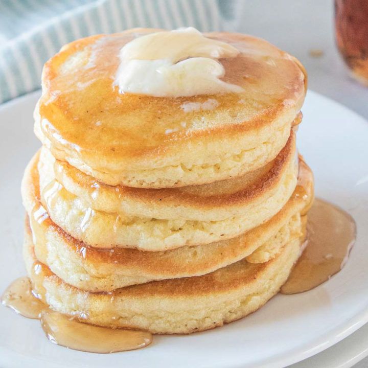 a stack of pancakes on a plate with butter and syrup drizzled on top