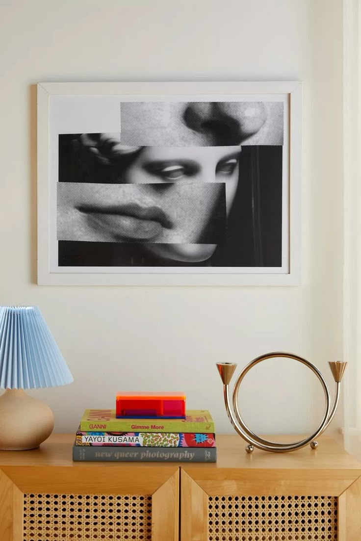 a table with books and a lamp on it next to a wall mounted photo in a room