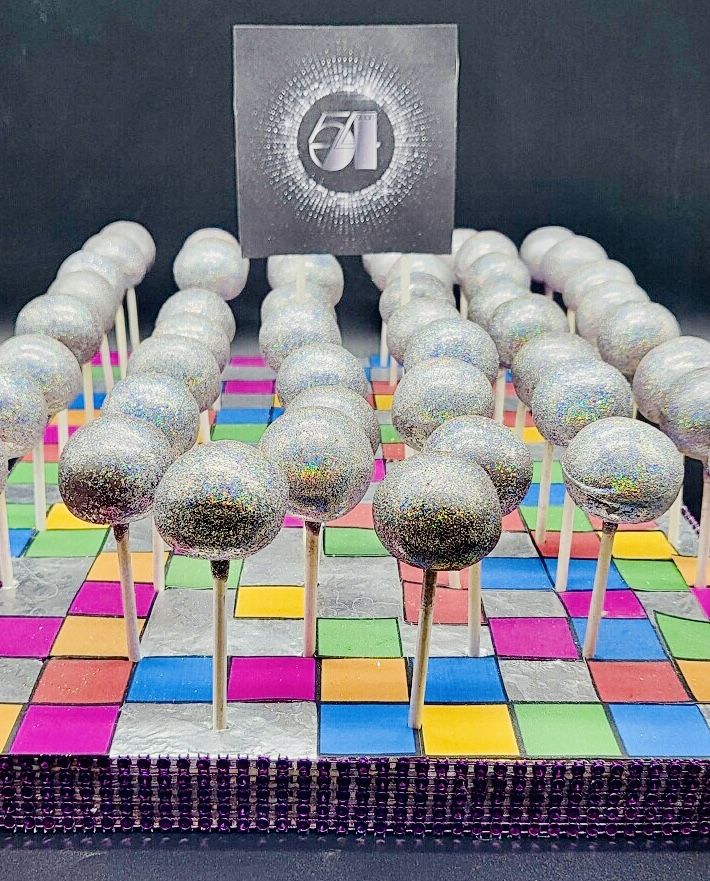 there are many lollipops that are on the colorful tablecloth with silver decorations