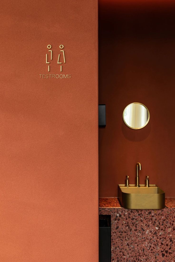 a bathroom with a sink, mirror and red wall in the background that says it's restroom