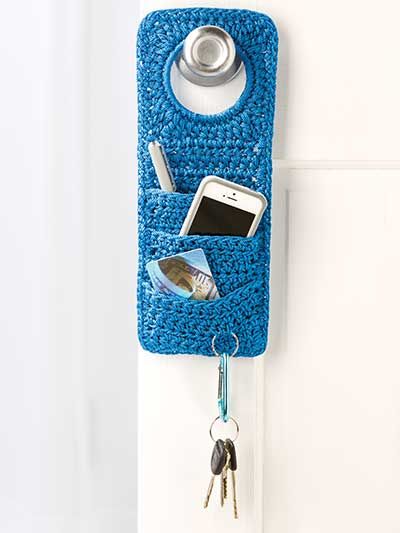 a cell phone holder hanging on the side of a door with two keys in it