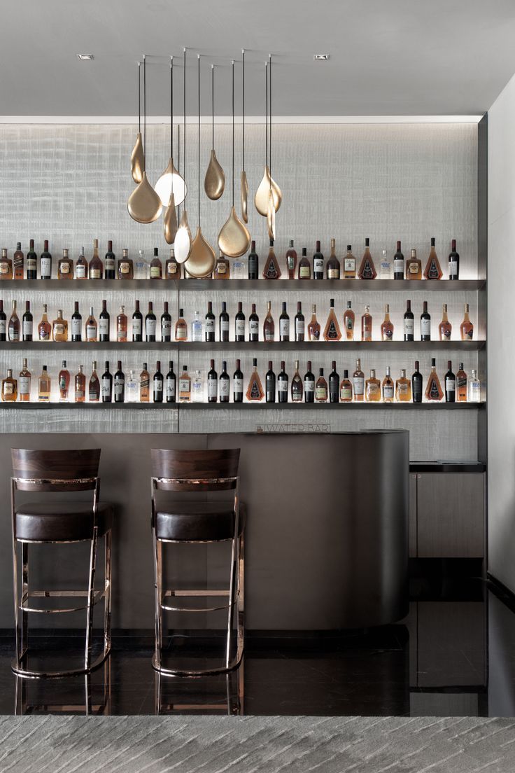 the bar is full of bottles and hanging utensils, along with two stools