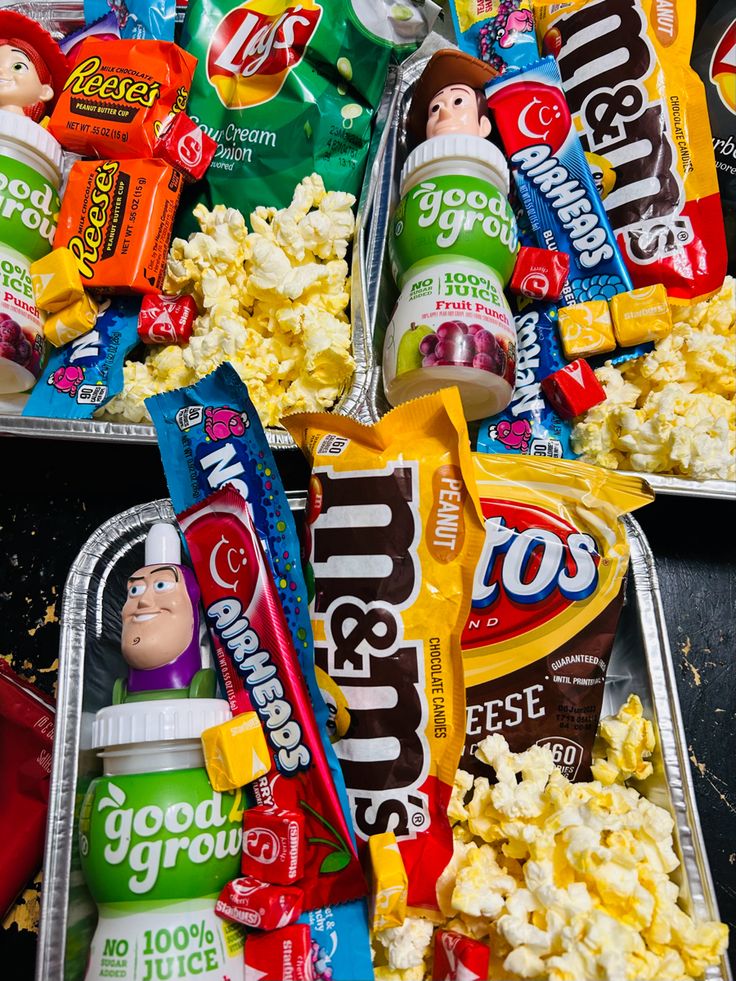 two trays filled with different types of snacks and candy bars on top of each other