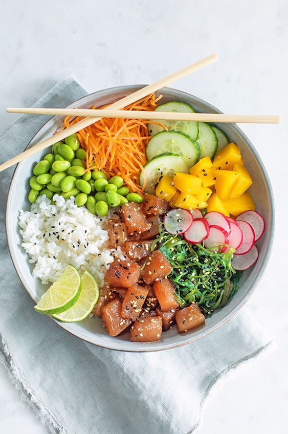 a bowl filled with rice, meat and veggies next to chopsticks