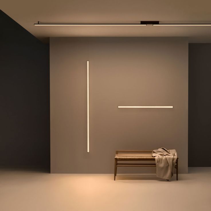 an empty room with a bench and lights on the wall, in front of it