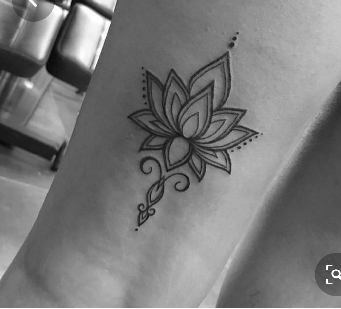 a black and white photo of a woman's leg with a lotus tattoo on it