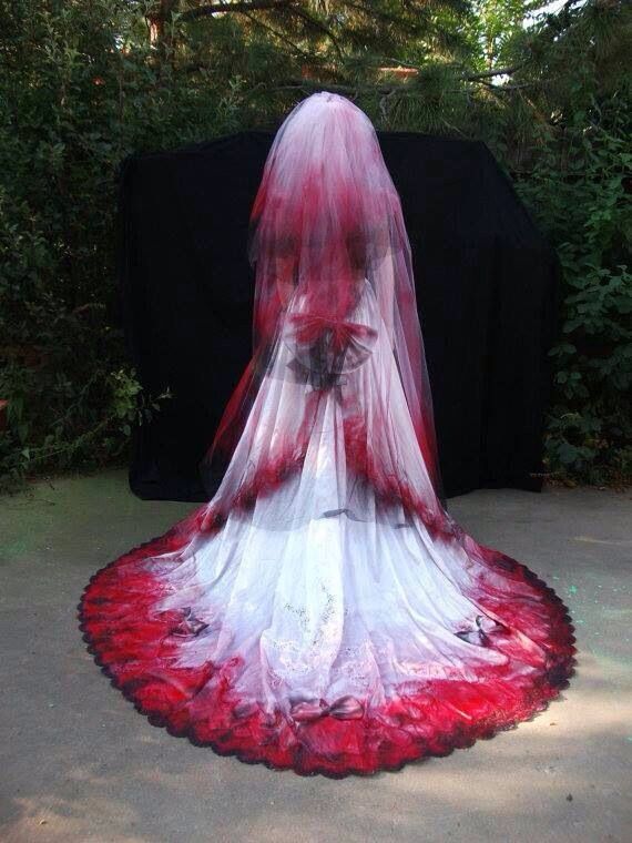 a woman in a white and red wedding dress standing on the ground with her veil draped over her head