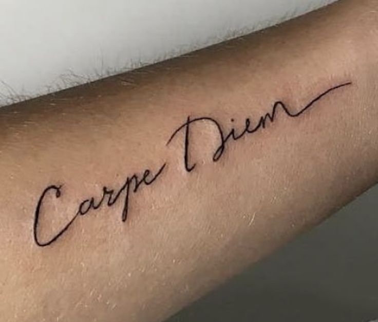 a person with a tattoo on their arm that says carpe dien in cursive writing