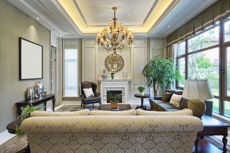 an elegant living room with chandelier, couches and fireplace in the center