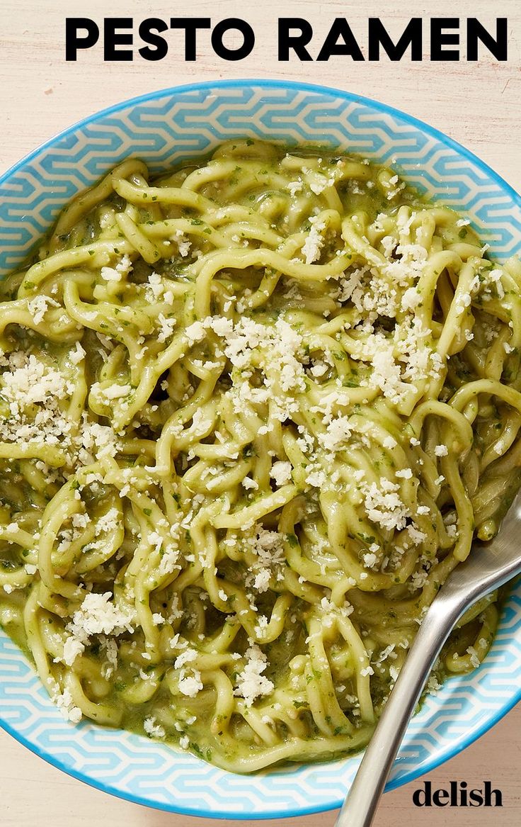 pasta with pesto and parmesan cheese in a blue bowl on a wooden table