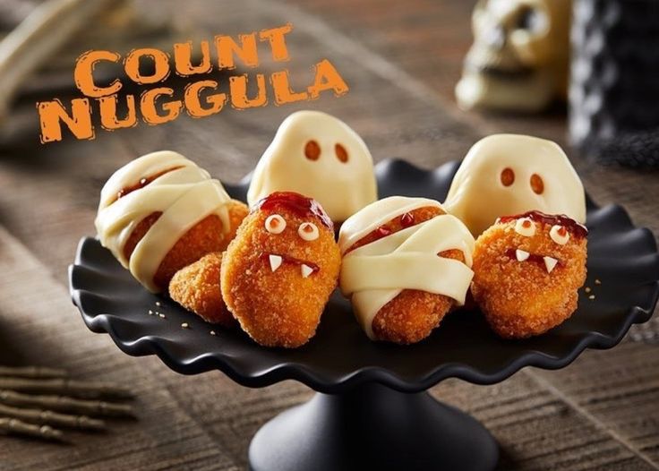 three donuts decorated like ghost faces on a black plate with the words count n'nuggla