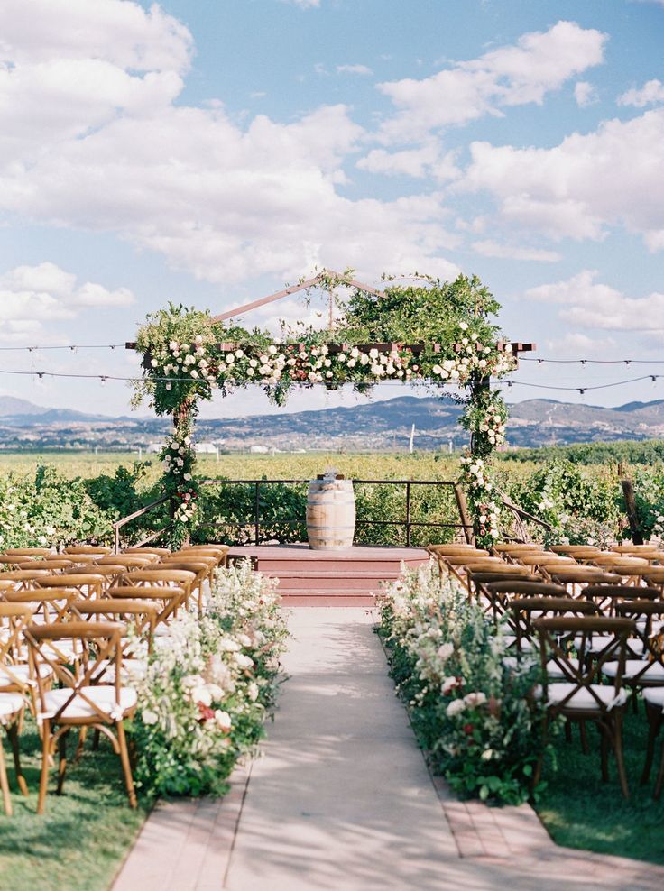 an outdoor ceremony setup with wooden chairs and flowers