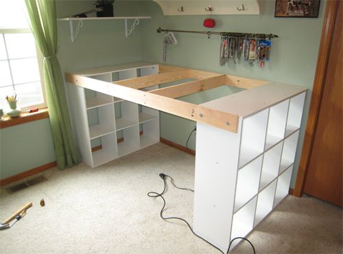 an unfinished desk in the corner of a room with shelves on either side and a window behind it