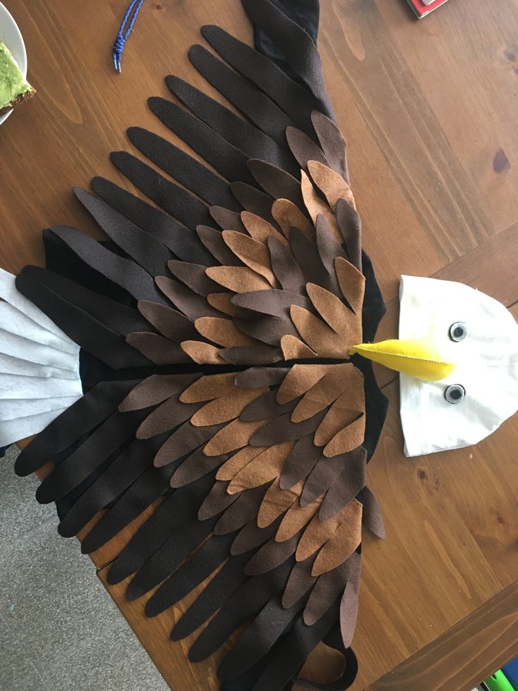 an eagle made out of leather and paper mache on a wooden table with scissors