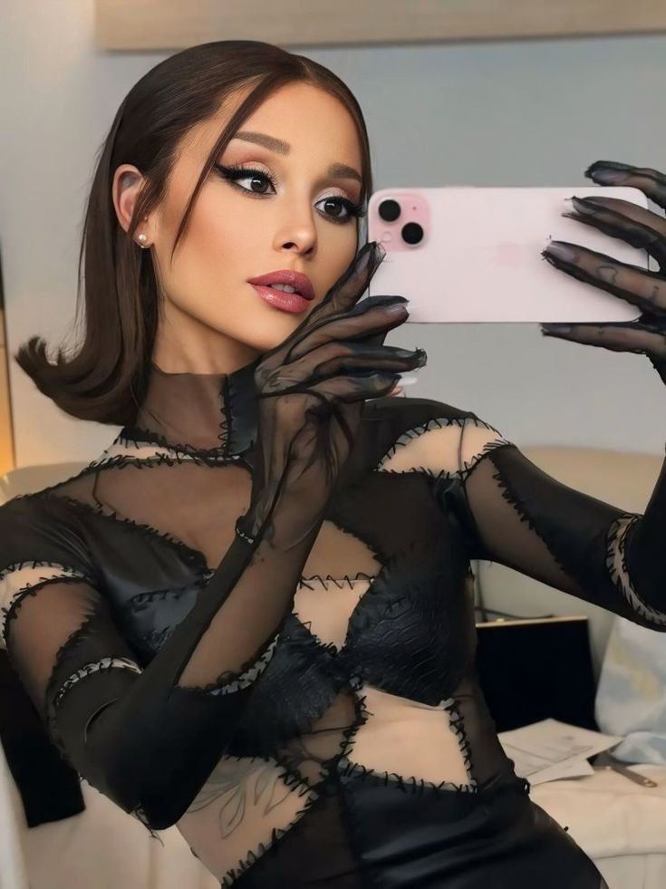 a woman taking a selfie with her cell phone wearing black gloves and sheer dress