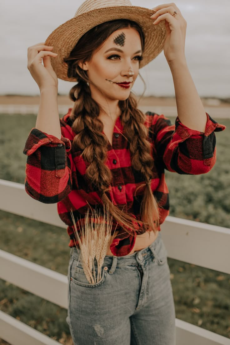 a woman with long hair wearing a red and black plaid shirt standing in front of a fence