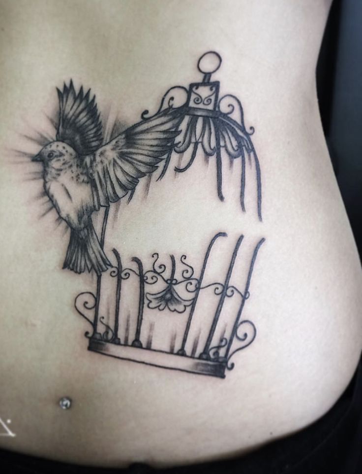 a woman's stomach with a bird in a cage tattoo on it