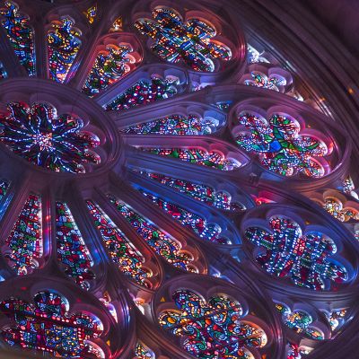 a large stained glass window inside of a cathedral with many lights on it's sides