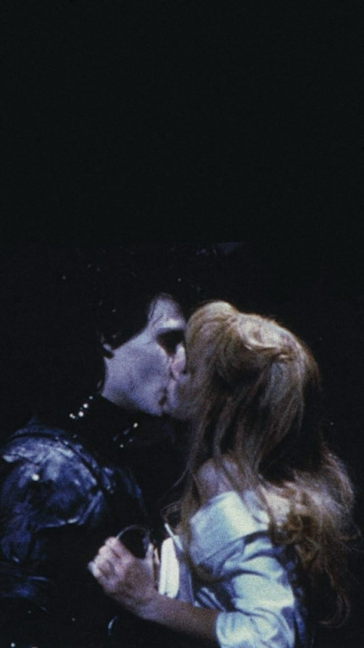 two people kissing each other in front of a black background