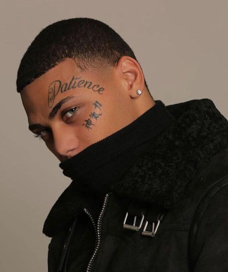 a man with tattoos on his face and neck looking to the side while wearing a black jacket